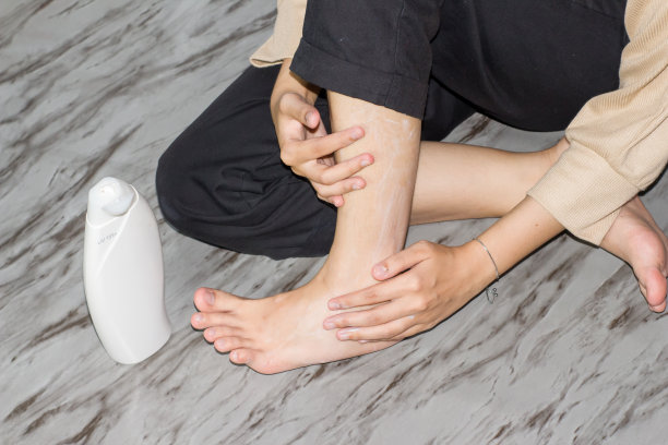 戴头巾的年轻女性涂抹腿霜、乳液或保湿霜的女性。皮肤护理。美女脚上涂着奶油图片下载