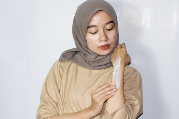 年轻的戴头巾妇女使用皮肤护理图片下载