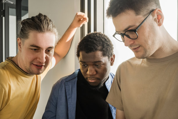 一个年轻的开发人员把新的项目任务交给他的合作伙伴。商务人士正在办公室讨论一个新的商业项目。编码技术，网站设计。成功的多元化团队合作图片下载