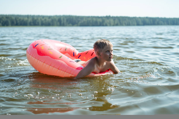 快乐可爱的白人男孩游泳与橡胶充气环。在湖边度假图片下载