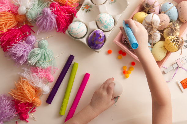 孩子们的手用春天装饰桌面视图的元素绘制复活节彩蛋图片下载