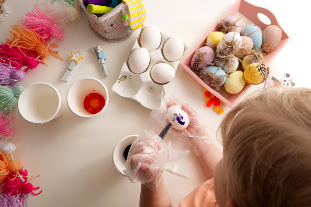 孩子们的手用春天装饰桌面视图的元素绘制复活节彩蛋图片下载