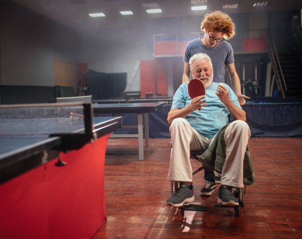 坐在轮椅上的爷爷和孙子一起打乒乓球图片下载