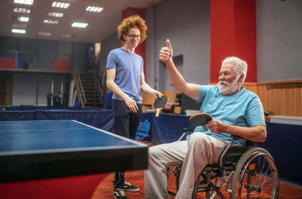 坐在轮椅上的爷爷和孙子一起打乒乓球图片下载