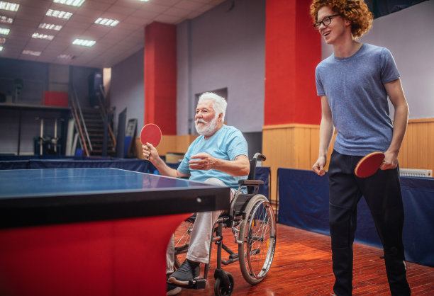 坐在轮椅上的爷爷和孙子一起打乒乓球图片下载