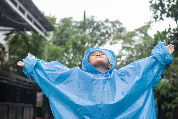 小男孩在雨中穿着雨衣在户外玩耍图片下载