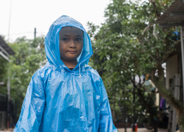 小男孩在雨中穿着雨衣在户外玩耍图片下载