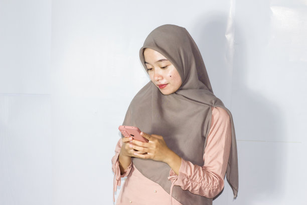 年轻的面纱妇女使用电话的肖像，孤立的背景图片下载