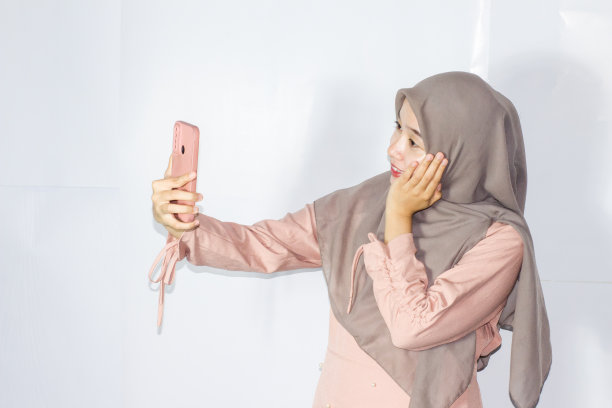 年轻的面纱妇女使用电话的肖像，孤立的背景图片下载