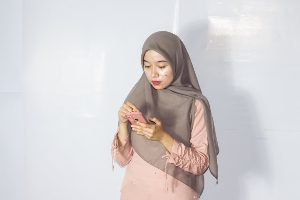 年轻的面纱妇女使用电话的肖像，孤立的背景图片下载