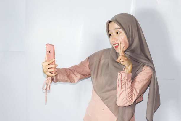 年轻的面纱妇女使用电话的肖像，孤立的背景图片下载