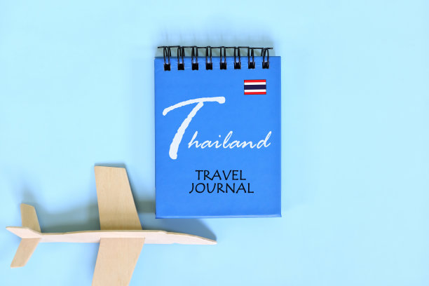泰国旅行日记写在蓝色记事本与国旗和木制飞机。极简的平面构图。图片下载