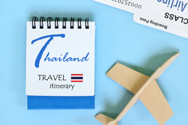 泰国旅行计划或行程，写在蓝色记事本上，上面有国旗和木制飞机。图片下载