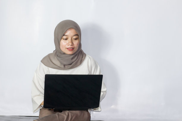 年轻的头巾妇女使用笔记本电脑的肖像图片下载