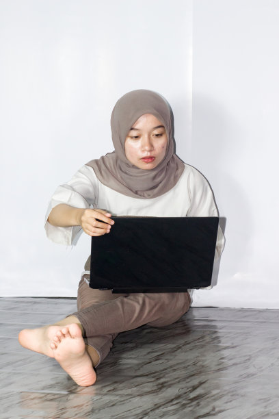 年轻的头巾妇女使用笔记本电脑的肖像图片下载