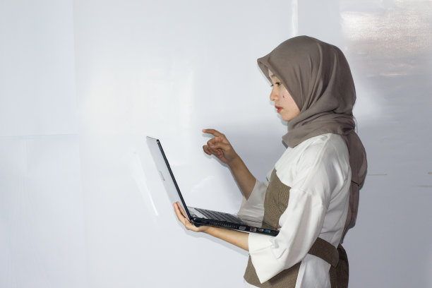 年轻的头巾妇女使用笔记本电脑的肖像图片下载