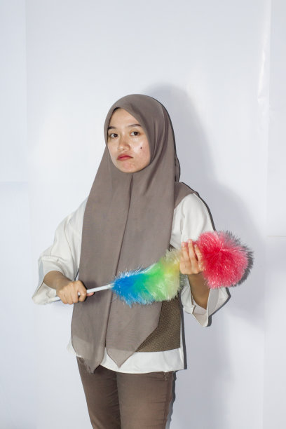 年轻女子的肖像在希贾布拿着抹布清洁，孤立的背景图片下载