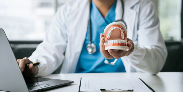 年轻的男牙医抱着牙齿模型。图片下载