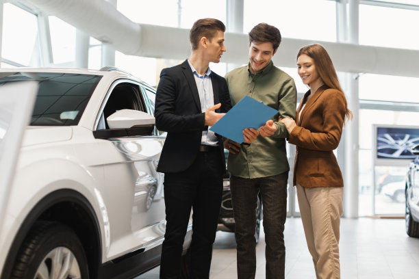 幸福的年轻夫妇购买新车，咨询销售人员在汽车经销店图片下载