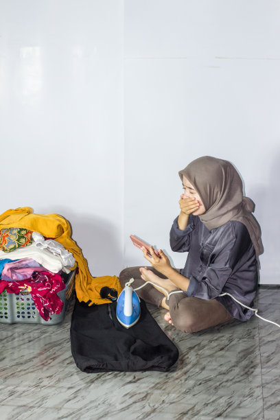 年轻的头巾妇女熨烫衣服，孤立的背景图片下载