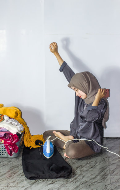 年轻的头巾妇女熨烫衣服，孤立的背景图片下载