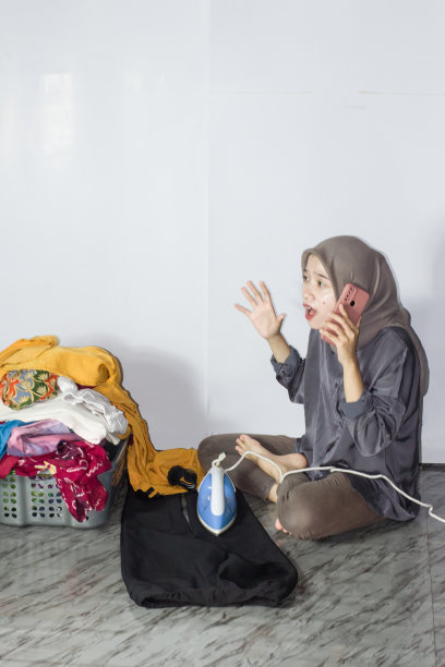 年轻的头巾妇女熨烫衣服，孤立的背景图片下载