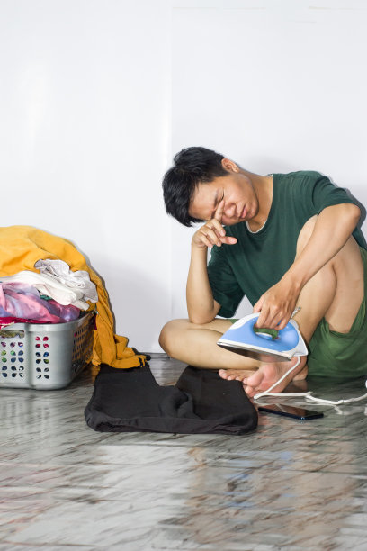年轻男子熨衣服，孤立的背景图片下载