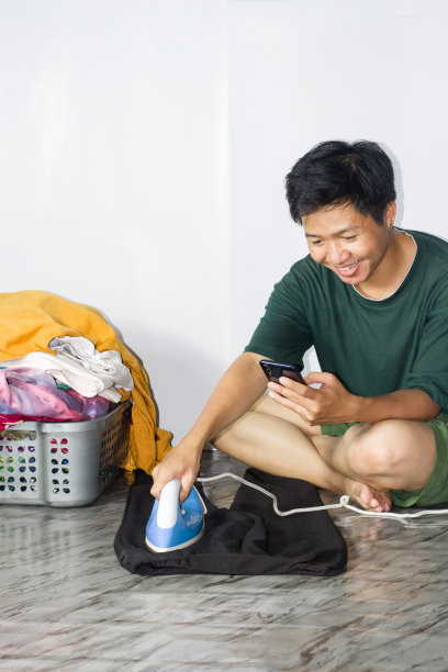 年轻男子熨衣服，孤立的背景图片下载