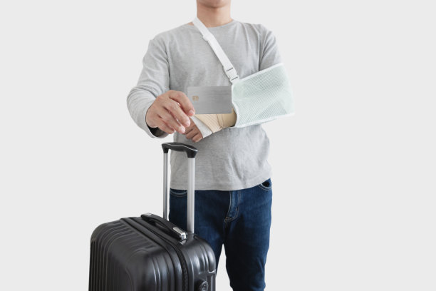 旅游保险概念。一名男子手带夹板受伤，手臂骨折，显示空空白卡，带着行李，隔离在白色背景上图片下载