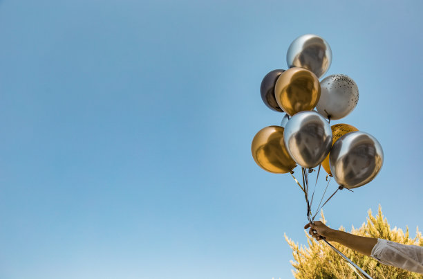 银色和金色的镀铬气球在户外蓝色的天空背景图片下载