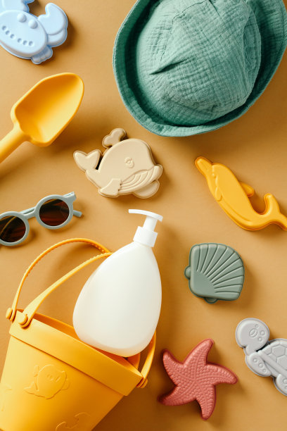 儿童防晒乳液瓶和黄色背景的沙滩玩具。平铺，俯视图。图片下载