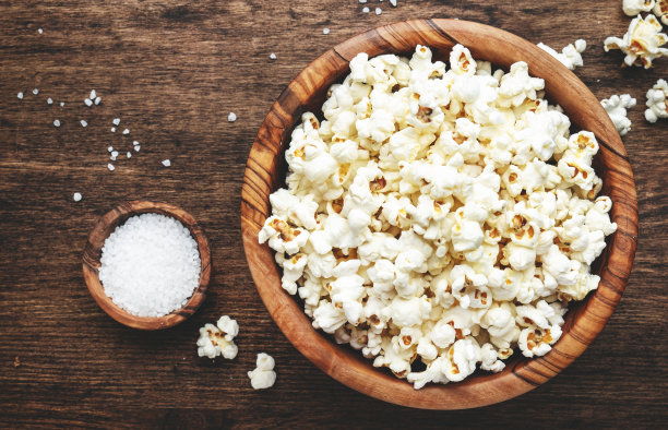 木碗里的咸爆米花，不健康的食物，木制厨房桌子背景，俯视图图片下载