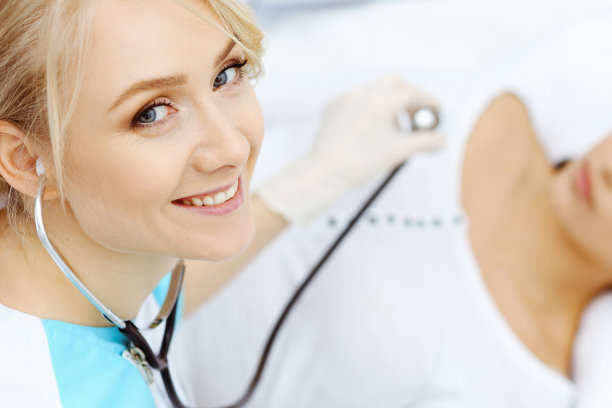 女医生和年轻女病人在医院。医生检查躺在床上的女孩，从上面看图片下载