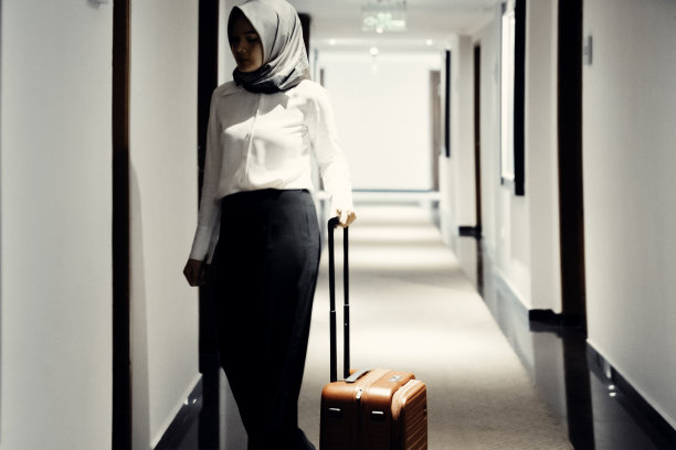 女商人带着行李箱在酒店走廊图片下载