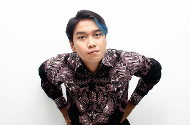 一个快乐而惊讶的亚洲男子蓝色偷看boo头发穿着蜡染衬衫充满快乐的表情。图片下载