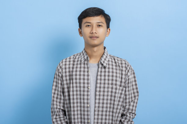 年轻的亚洲大学生携带书籍和背包孤立在蓝色背景图片下载