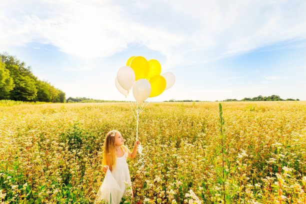 一个可爱的小女孩紧紧地抱着一大捆氦气球。庆祝概念，生日。图片下载