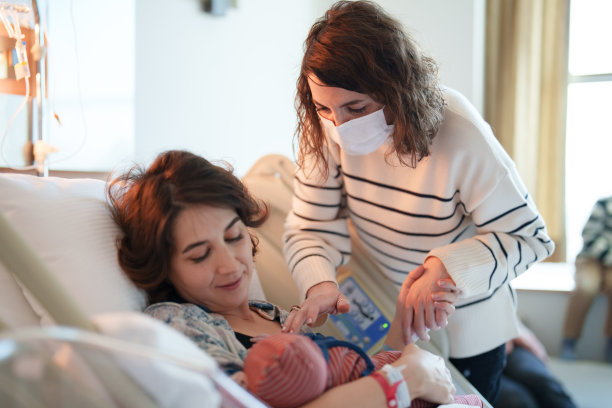 一名妇女在医院帮助她的妹妹母乳喂养图片下载