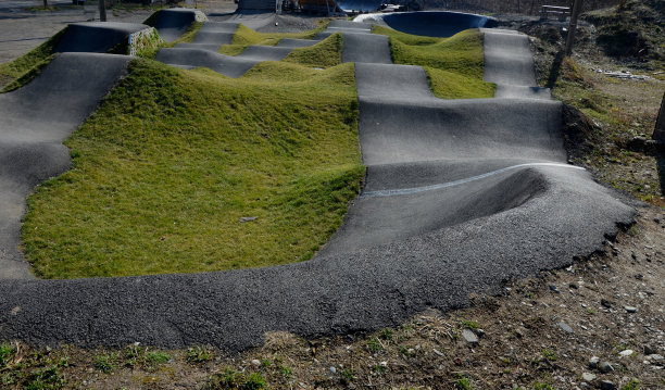 在模块化的泵道轨道上，使用泵(上下移动)代替踏板和弹跳来移动自行车、滑板、滑板和直排旱冰鞋图片下载