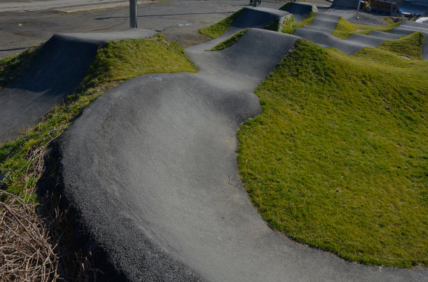 在模块化的泵道轨道上，使用泵(上下移动)代替踏板和弹跳来移动自行车、滑板、滑板和直排旱冰鞋图片下载