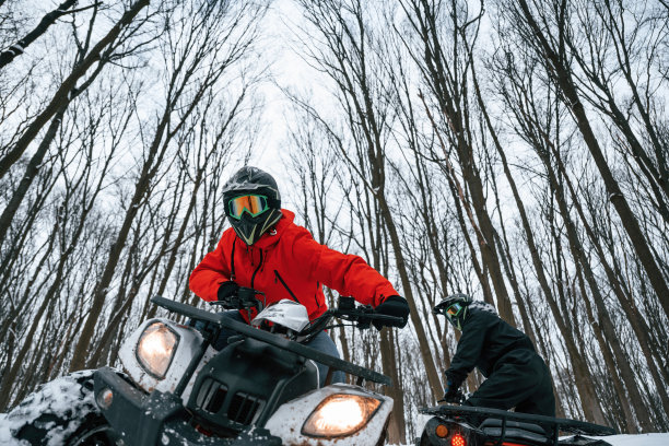 在越野路上。两个人在冬天的森林里骑着全地形车图片下载