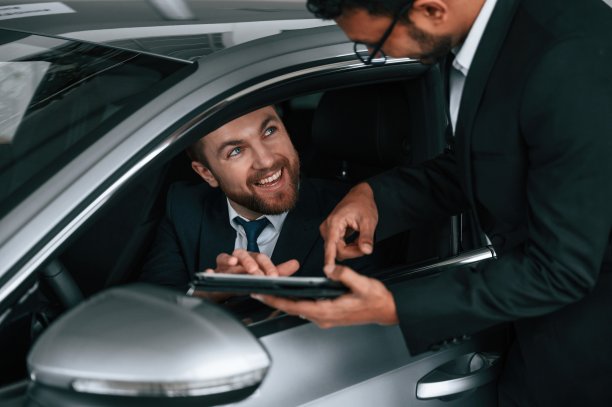 一名男子坐在新车里，顾问正在向客户展示平板电脑上的细节和数据图片下载