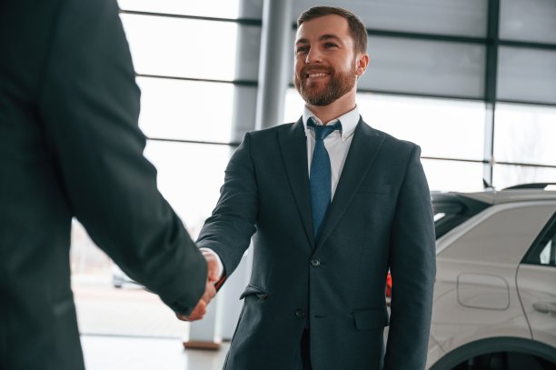 两个商人正站在汽车展示厅里做交易，握手图片下载
