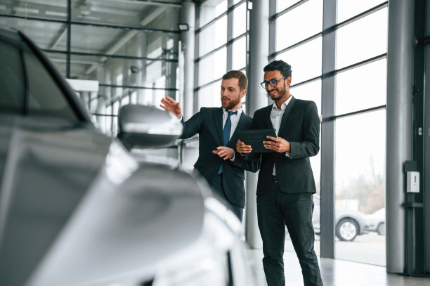 看那辆车。一名男子在汽车陈列室向顾客咨询图片下载