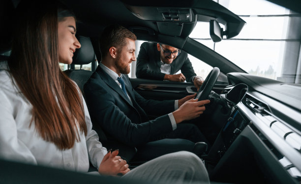 侧视图。汽车展示厅的工作人员正在向坐在车里的一男一女咨询图片下载