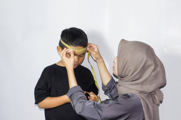 戴头巾的年轻女子在测量一个男孩的身体图片下载