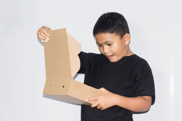 男孩拿着礼品盒，快乐微笑的男孩拿着惊喜礼物的肖像图片下载