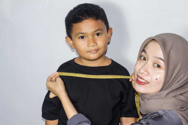 戴头巾的年轻女子在测量一个男孩的身体图片下载