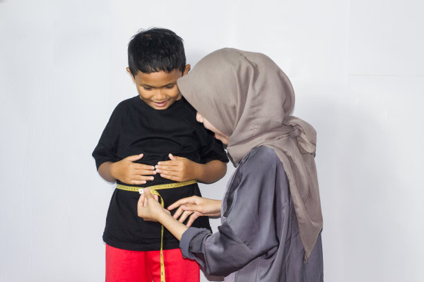 戴头巾的年轻女子在测量一个男孩的身体图片下载