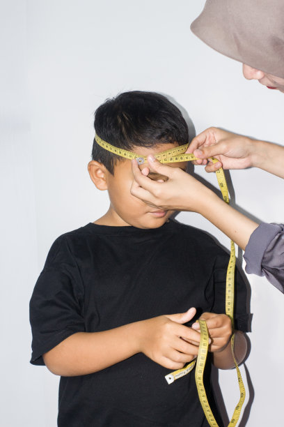 戴头巾的年轻女子在测量一个男孩的身体图片下载